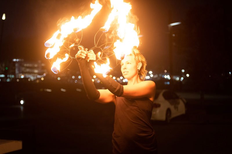 fire performer holds fire fans